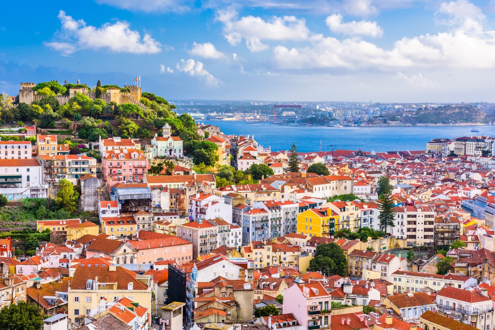 Lisbon's Alfama rooftops beneath São Jorge Castle with the Tagus river beyond