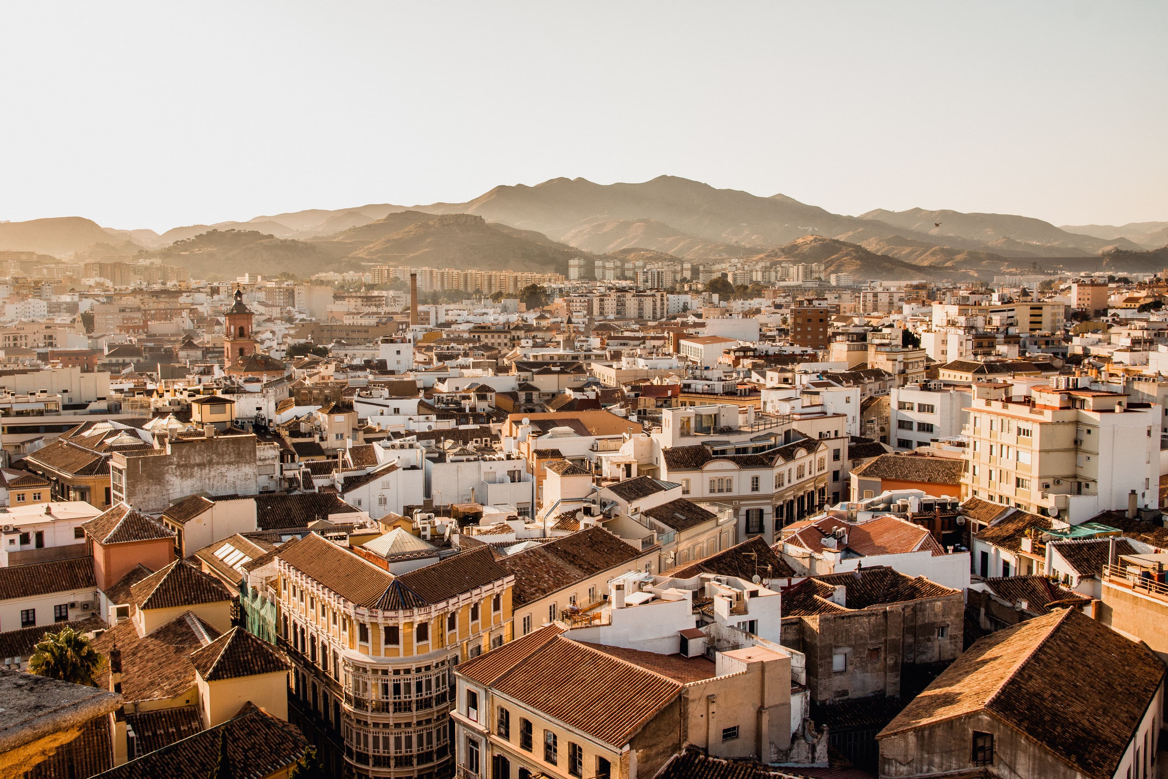 Spanish city rooftops at golden hour with mountains in the distance