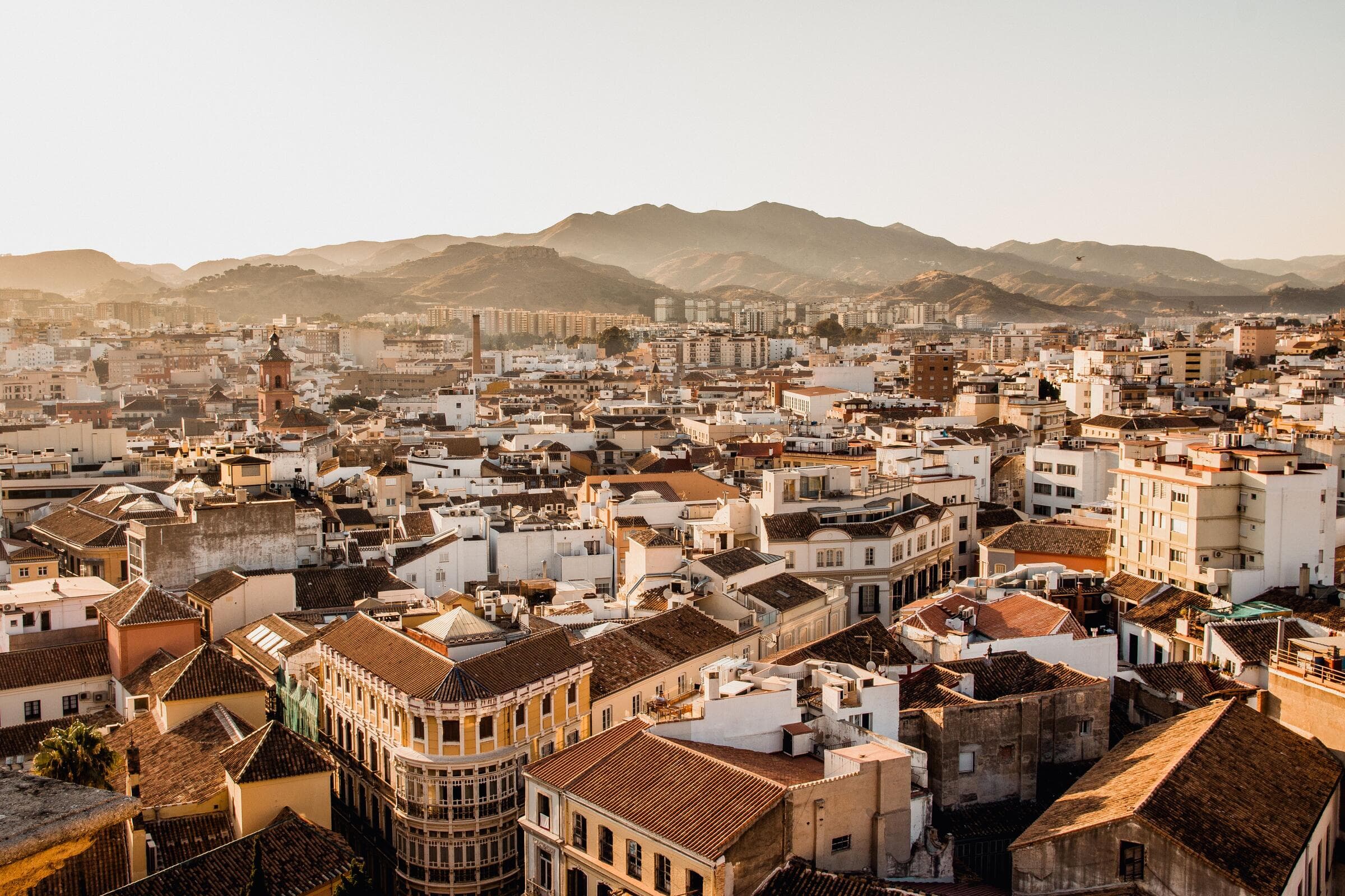 Spanish city rooftops at golden hour with mountains in the distance